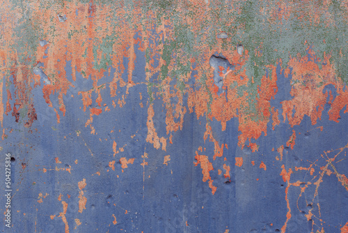 Grunge classic blue concrete background. Textured plaster wall. Orange and green elements in backdrop. Color of the year 2022 concept. Top view, layout for design. Surface with peeling shabby pattern.