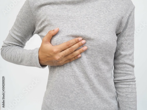 Young woman examining her breast for lumps or signs of breast cancer on white background. photo