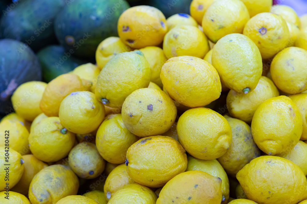 Pile of ripe lemons in market. Fresh fruits for sale.