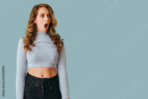 Valokuva portrait of young shocked woman with long curly hair studio