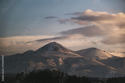 Landscape view of a mountain with snow, blue sky and some clouds