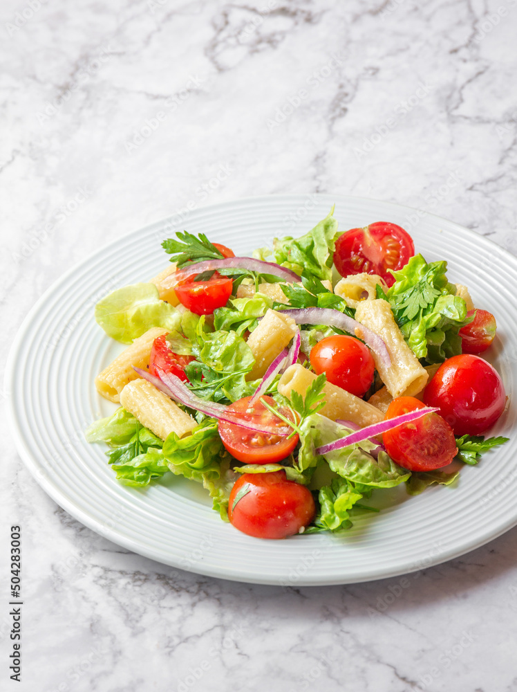 Lettuce tomato cherry salad with penne pasta.