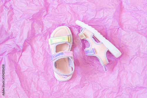 Stylish holographic sandals for kids on purple background. Shiny fashion summer shoes. Flat lay, Top view