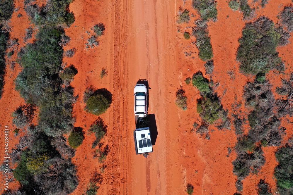 Aerial landscape drone view of 4WD vehicle towing an off road caravan driving on a sand dirt road - obrazy, fototapety, plakaty 