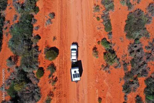 Fototapeta Aerial landscape drone view of 4WD vehicle towing an off road caravan driving on