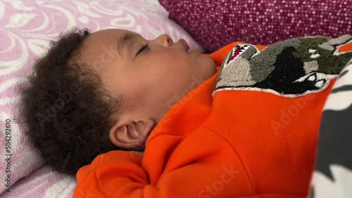 Exotic two year old african european child sleeping deeply in his bed photo