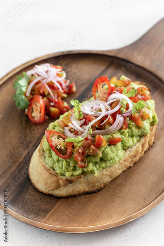 spicy chilli avocado guacamole on toast tapas on wood tray