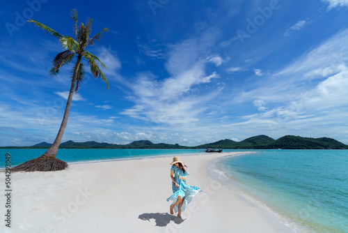 Asian woman wears a dress and travels to the beach in the summer alone on her vacation at andaman sea Laem Had Beach, Koh Yao Yai, Phang Nga, Thailand.