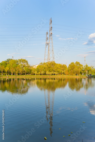 Power transmission tower reflected on the lake in the park