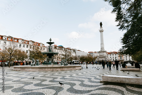 Praca do Rossio plaza square in Lisbon Portugal that is famous for its black and white rolling motion square mosaic, tourism, cafes, and Column of Pedro IV.  photo