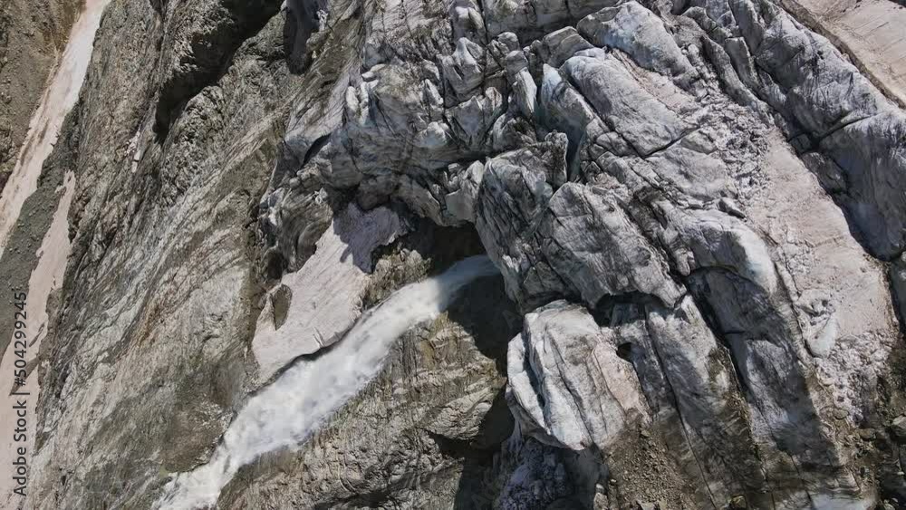 A beautiful waterfall in the upper reaches of the Tanadon Gorge. Hanging glacier Tanantseti from under which flows a stormy water stream. Caucasus. Digoria, North Ossetia-Alania, Russia. Drone view A beautiful waterfall in the upper reaches of the Tanadon Gorge. Hanging glacier Tanantseti from under which flows a stormy water stream. Caucasus. Digoria, North Ossetia-Alania, Russia. Drone view