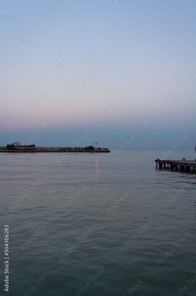 The embankment of the city of Yalta. The lighthouse and the sea. Vertical photo.