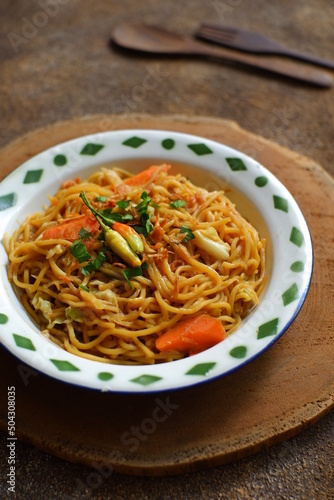 a plate of noodles cooked in sauce with vegetables 