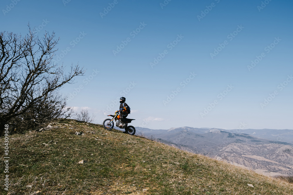 Obraz premium Active elderly man riding enduro motocross motorcycle pit bike in beautiful mountains hills landscape