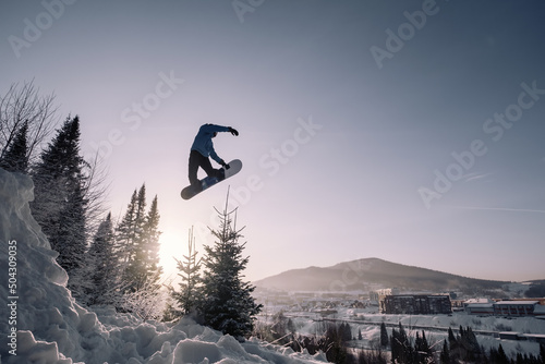 Fotografía Snowboarder making high big air jump with grab in clear blue sunny sky during su