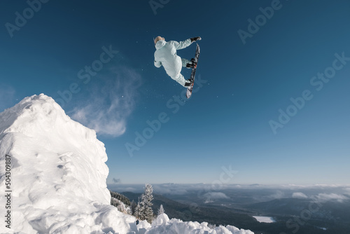 Fotografie Snowboarder pro-rider jumping  high flip big air in clear blue sunny sky above m