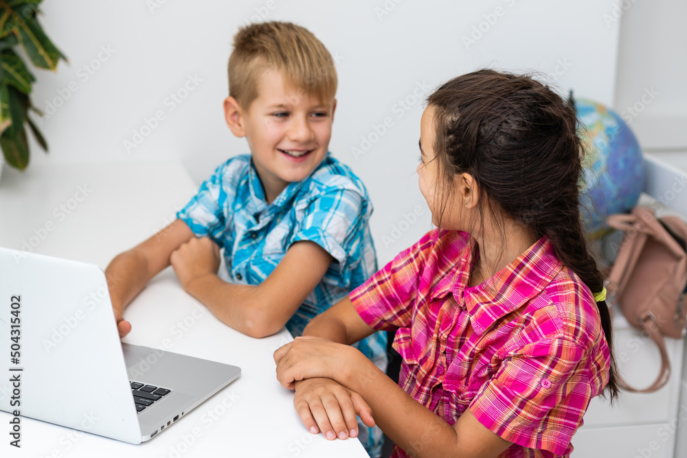 Young boy with a laptop computer sitting near a girl Young boy with a laptop computer sitting near a girl