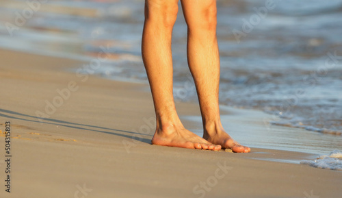 Tela Feet of a man lying on a sunbed near the sea.