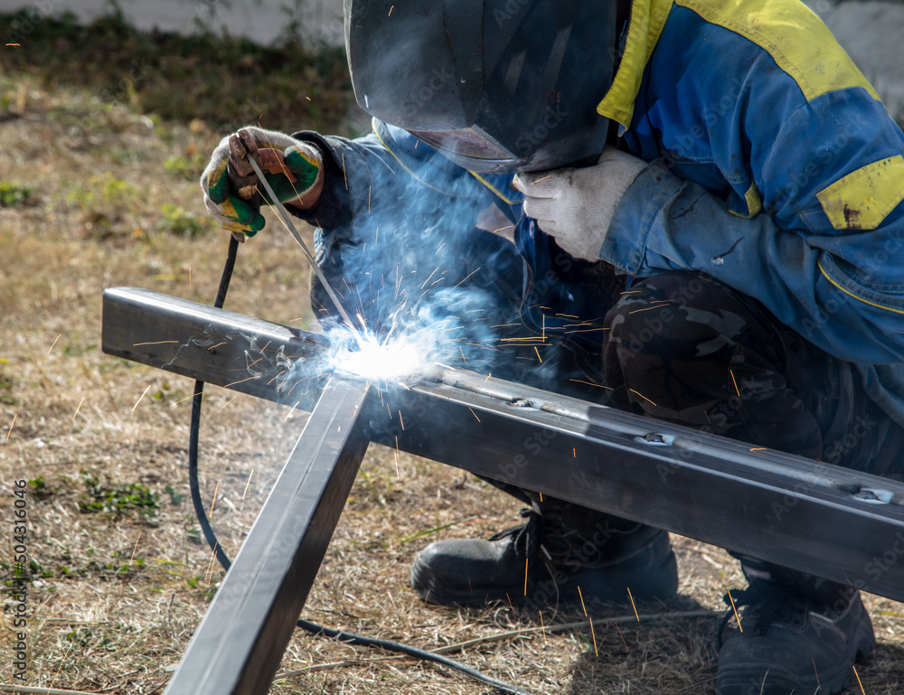 A worker welds metal at a construction site. Technology A worker welds metal at a construction site. Technology