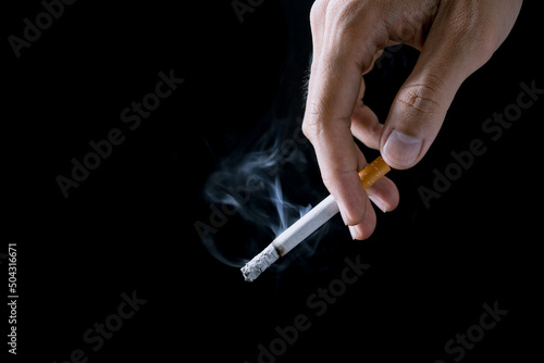 Cigarette.Closeup hand of man holding a cigarette.tobacco cigarette butt no the floor.World on tobacco day.Sign of stop smoking for no smoking day.