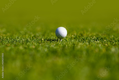 Golf ball close-up in soft focus at grass. Sport golf ball on background with copy space.