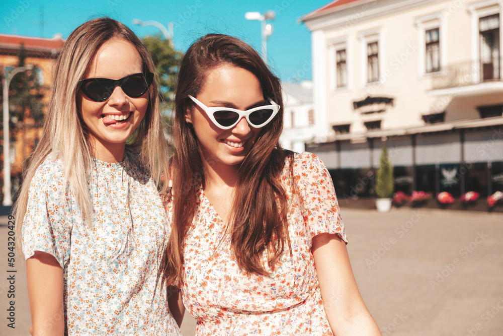 Two young beautiful smiling hipster female in trendy summer dresses.Sexy carefree women posing in the street. Positive pure models having fun at sunset, hugging and going crazy Two young beautiful smiling hipster female in trendy summer dresses.Sexy carefree women posing in the street. Positive pure models having fun at sunset, hugging and going crazy