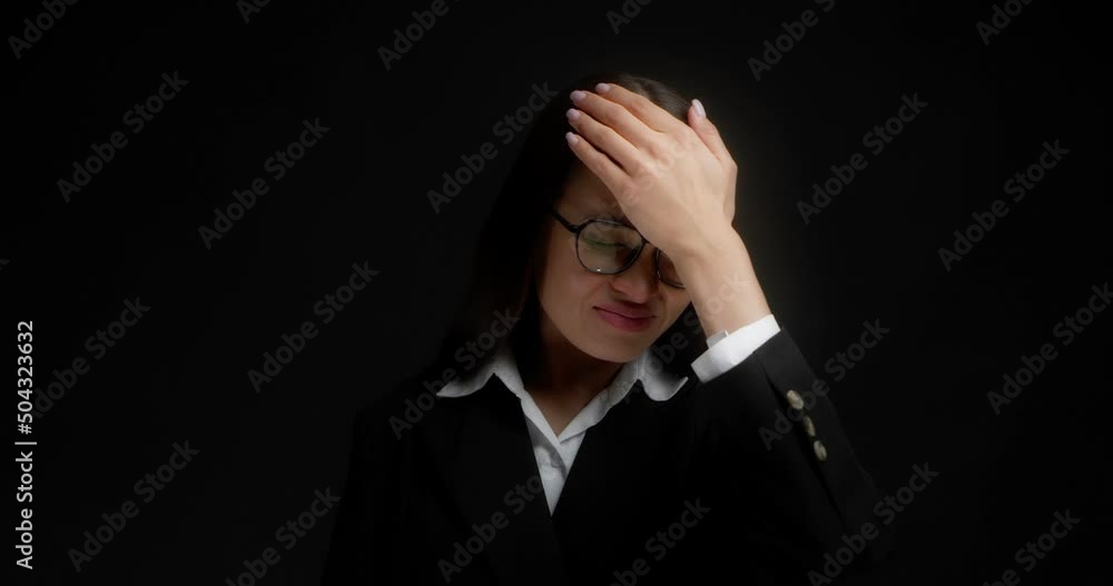 Business woman with long dark hair, glasses and office clothes forgot something, holds her forehead with her fist, bad memory. Isolated on a black background Business woman with long dark hair, glasses and office clothes forgot something, holds her forehead with her fist, bad memory. Isolated on a black background