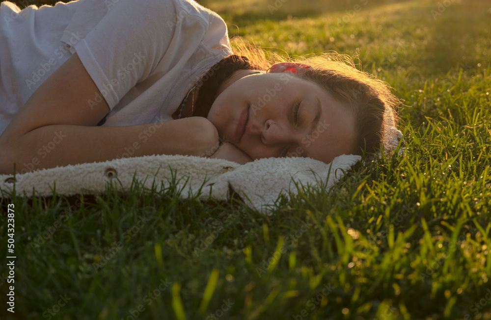Teenage girl sleeping on grass during sunset Teenage girl sleeping on grass during sunset
