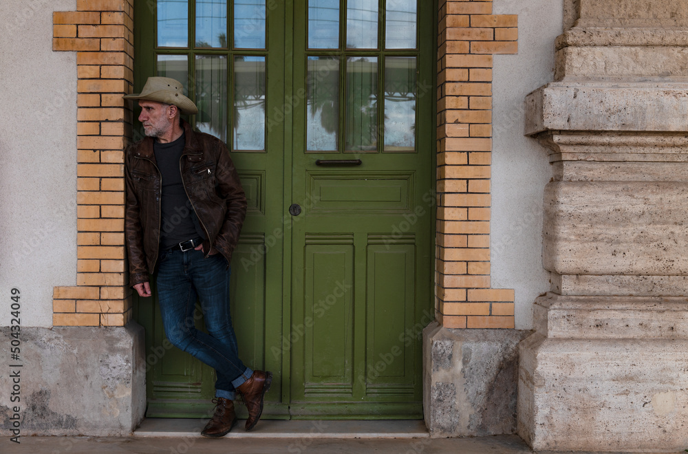Full length of adult man in cowboy hat standing on doorway Full length of adult man in cowboy hat standing on doorway