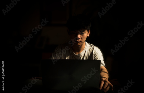 Portrait of teenage Asian boy using laptop indoor with sunlight and shadow