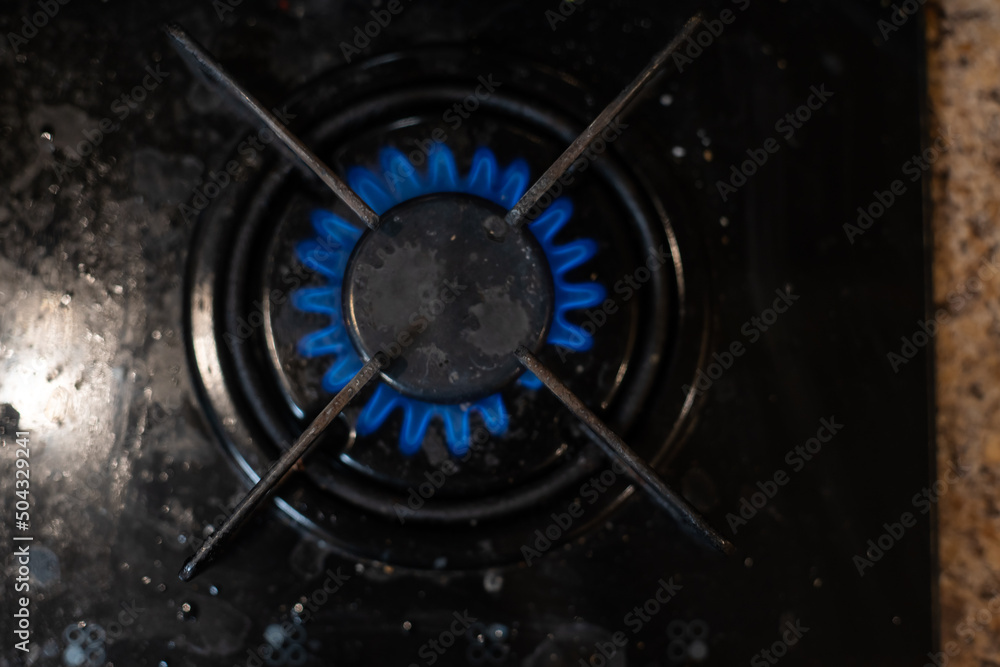 Closeup shot of blue fire from domestic kitchen stove top. Gas cooker with burning flames of propane gas. Industrial resources and economy concept