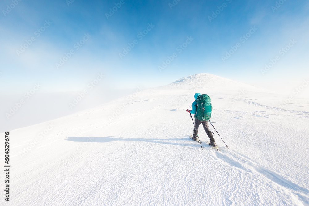 A woman walks in snowshoes in the mountains, winter trekking