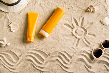 Sunblock, sunglasses and hat on summer sandy beach