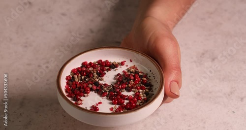 woman hand takes paprika hot pepper from bowl