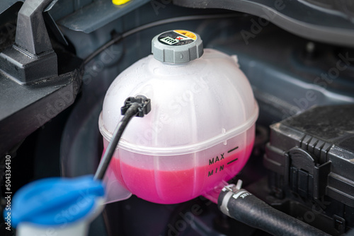 A car's engine coolant water supply box filled with pink color antifreeze liquid. Transportation equipment object photo. photo