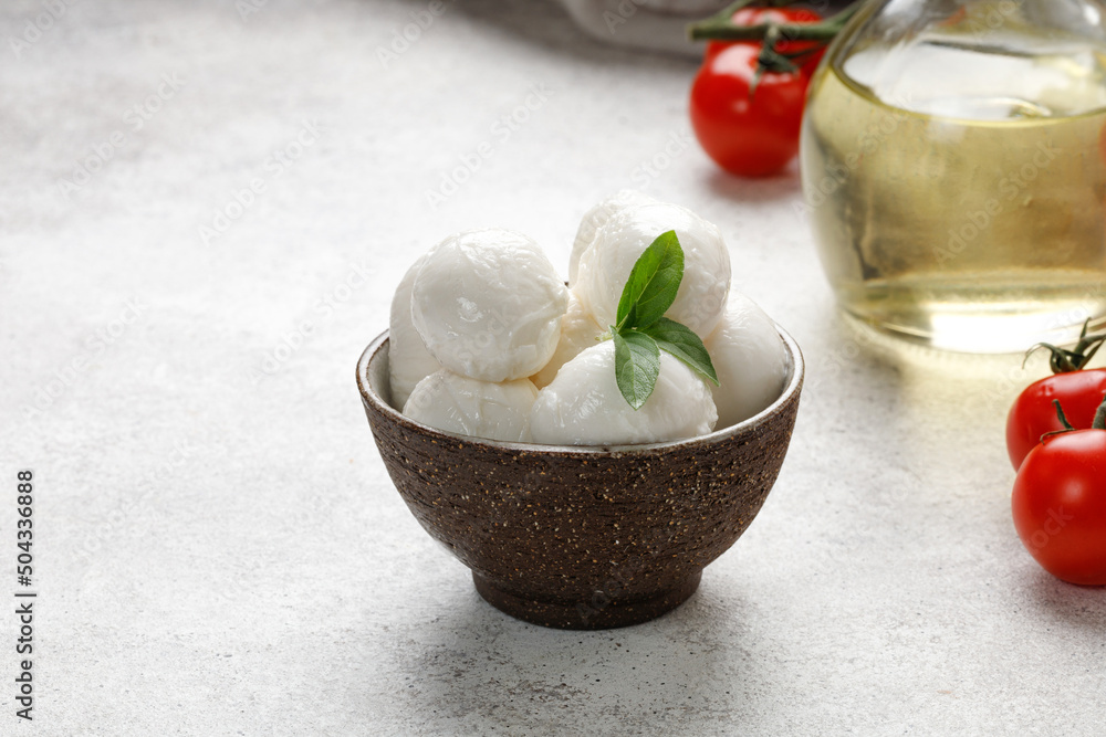 Mozzarella balls cheese on grey background with oil, basil and tomatoes. Italian cheese product, close up Mozzarella balls cheese on grey background with oil, basil and tomatoes. Italian cheese product, close up