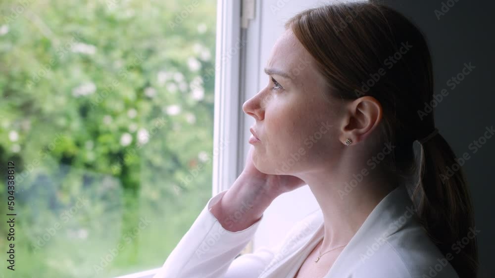 A bored woman looking out of the window in pensive thought. A bored woman looking out of the window in pensive thought.
