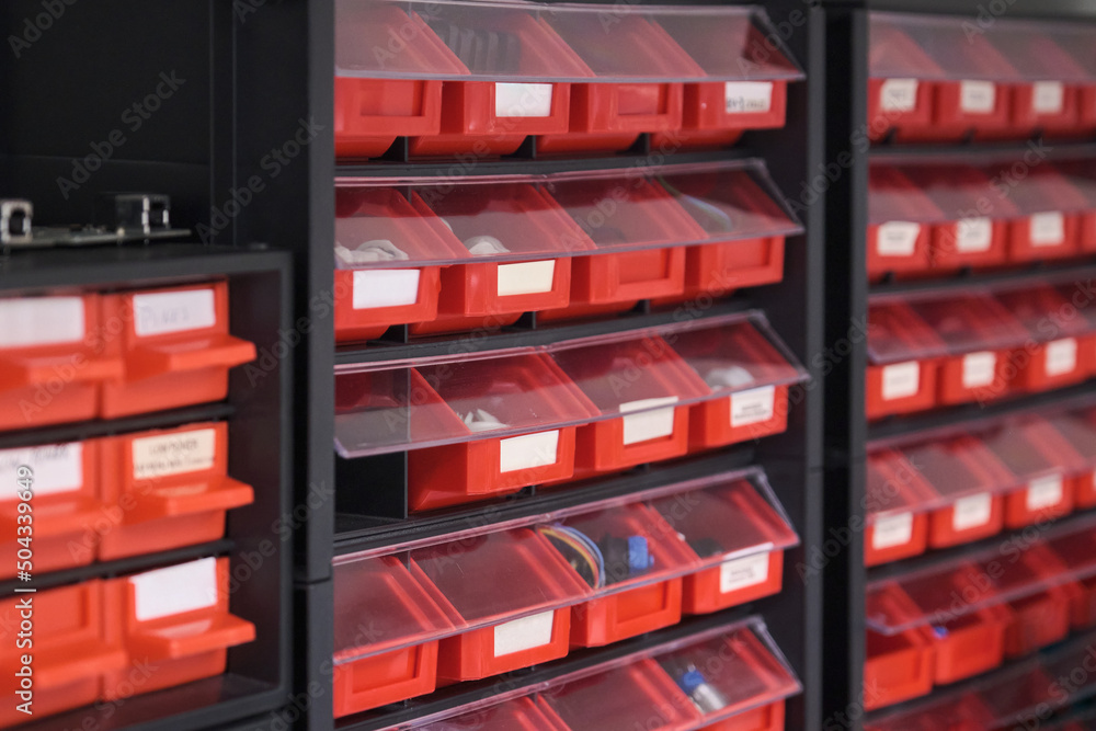 Screws, bolts, nuts, in red storage boxes in a workshop. Plastic