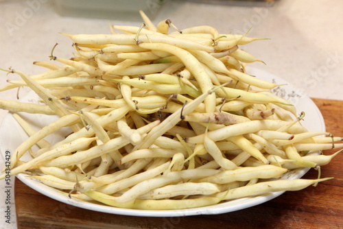 Fresh butter beans on a plate. Close up of yellow string beans in a white bowl