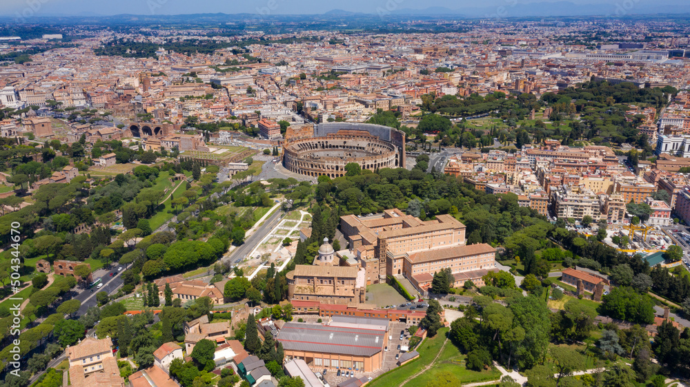 Aerial view of Colosseum and the Arch of Titus, in Italy, on a sunny day. These monuments of ancient Rome are a symbol of the city and visited by many tourists every day.