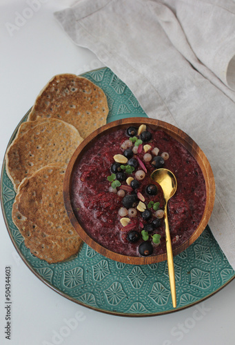 purple berry smoothie bowl in a wooden bowl and healthy green buckwheat pancakes
