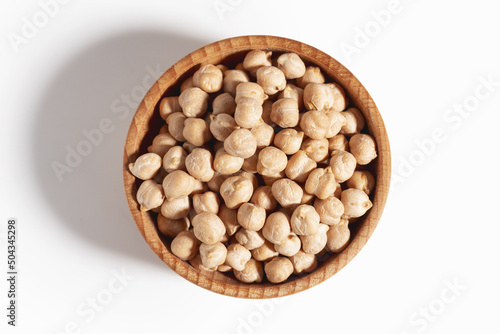 Wooden bowl filled with chickpea beans. Chickpea beans in bowl isolated on white background. View top.