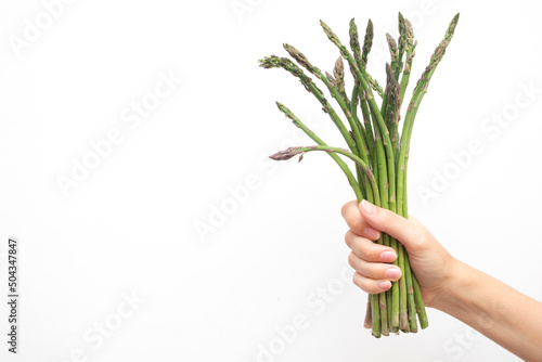 Womans hand holding asparagus isolated on white background