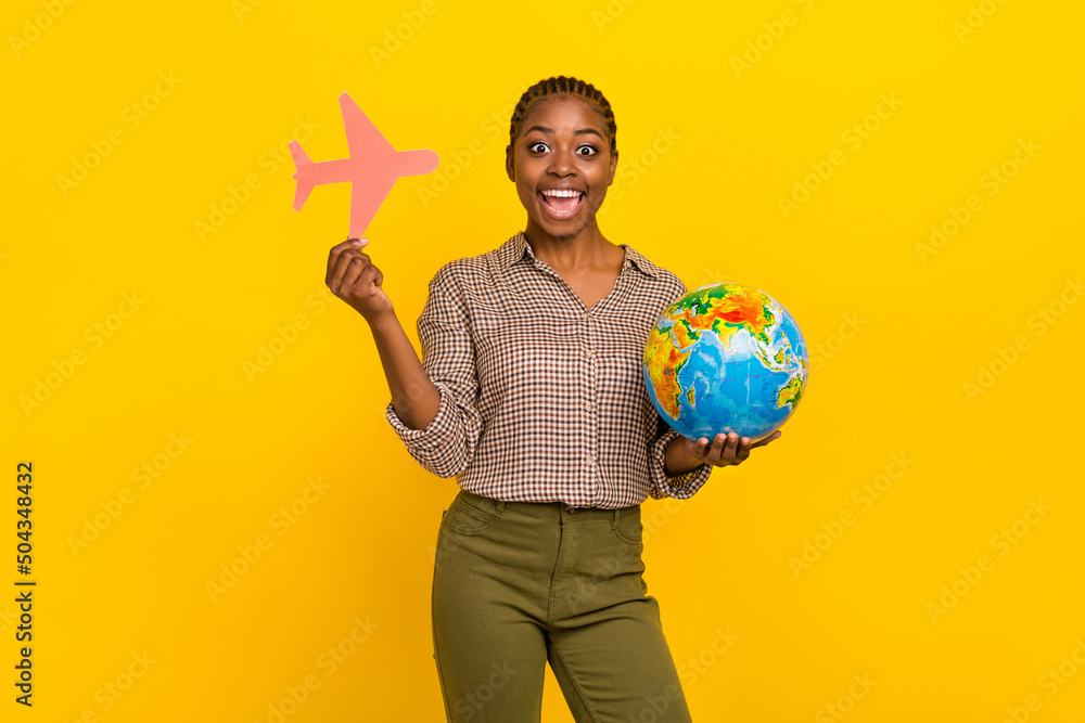 Fototapeta premium Photo of excited funny lady dressed checkered shirt rising paper plane holding globe isolated yellow color background