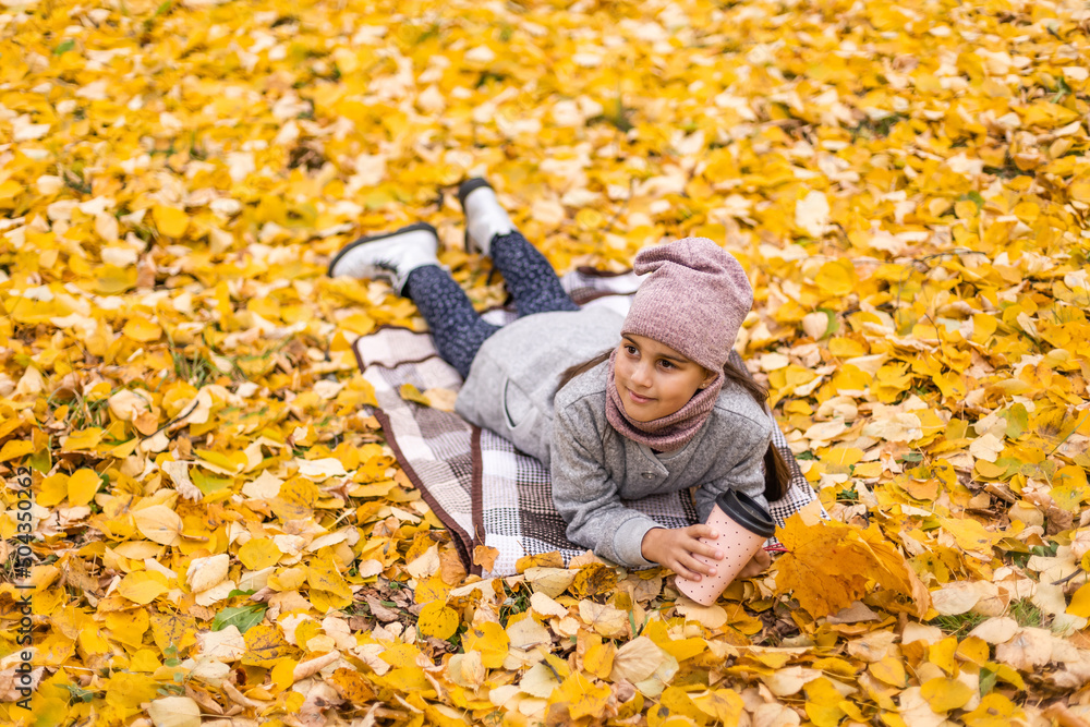 Little funny girl lies on yellow leaves in the forest. Child on a walk in the autumn park. Preschool girl Little funny girl lies on yellow leaves in the forest. Child on a walk in the autumn park. Preschool girl