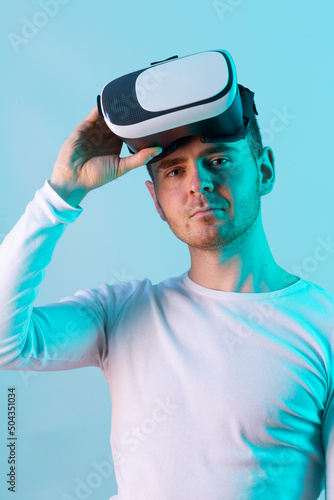 Modern young man experiencing virtual reality glasses in futuristic neon illuminated studio