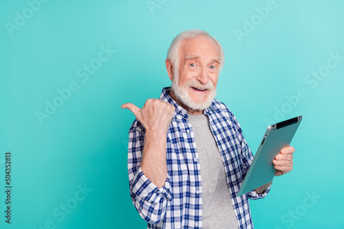 Photo of positive retired man advertise product in blank space wear checkered casual shirt isolated on teal color background