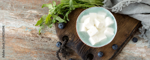 bowl with feta cheese cubes in brine on a wooden table