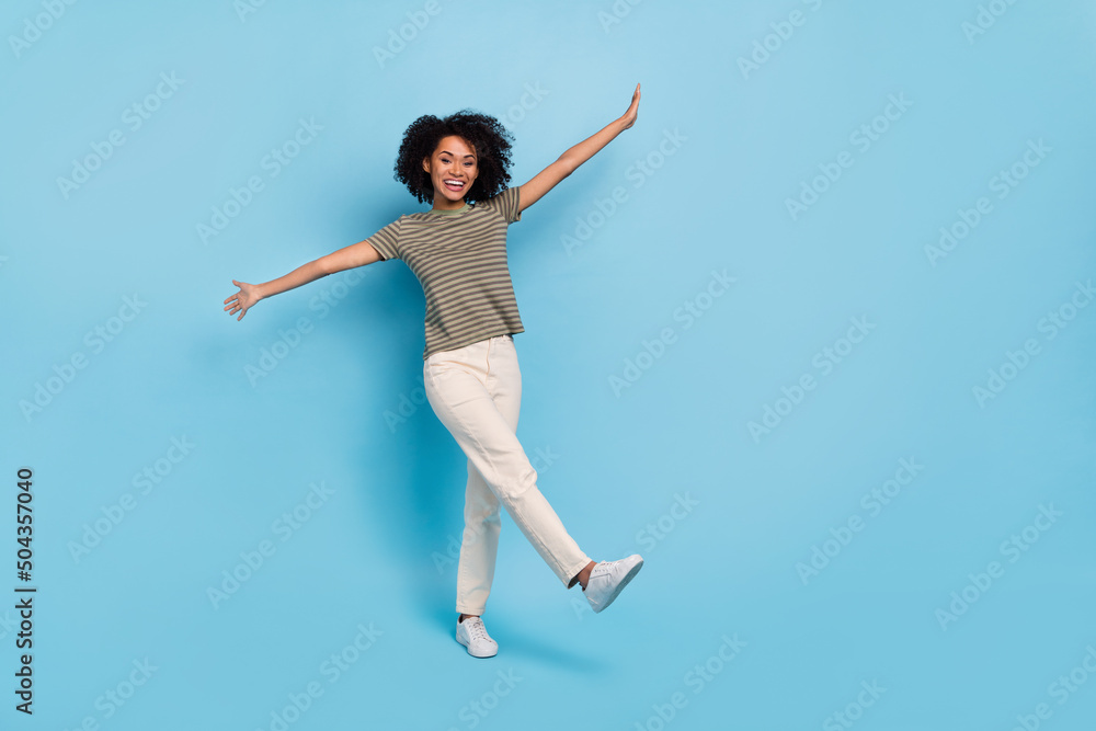 Full length photo of good mood lady hold hands playing flying plane isolated on blue color background Full length photo of good mood lady hold hands playing flying plane isolated on blue color background