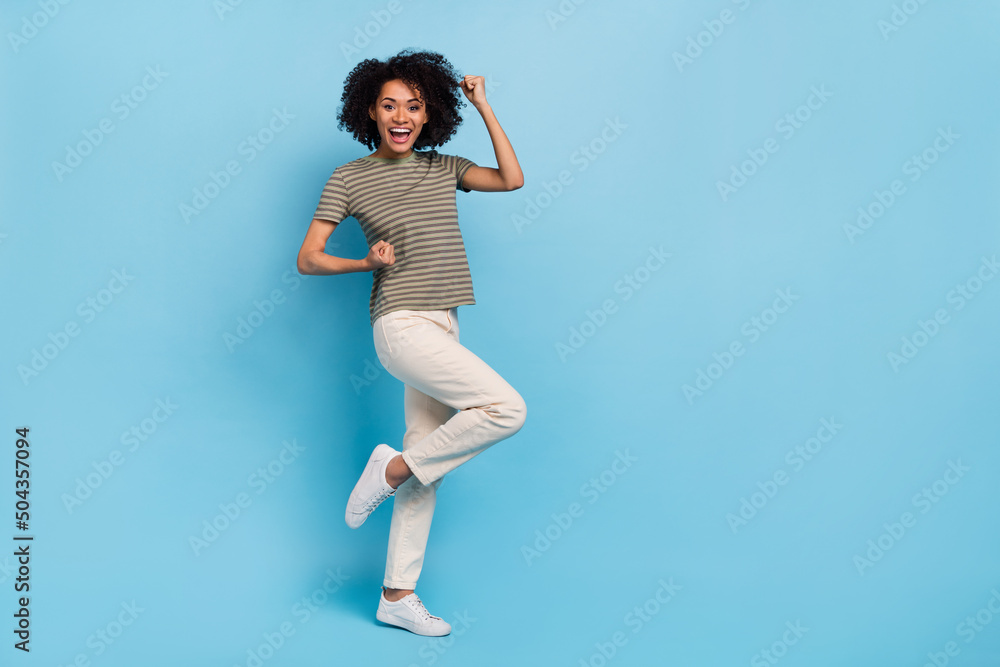 Full length photo of delighted lady rejoicing fist up win lottery isolated on blue color background Full length photo of delighted lady rejoicing fist up win lottery isolated on blue color background